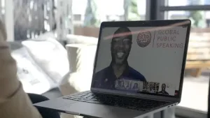 person looking at laptop with Global Public Speaking video playing
