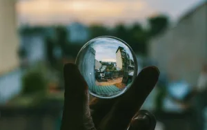 Closeup Thumb and Forefinger Holding Clear Glass Ball Amplifying Background Allison Shapira Clarity in Public Speaking LIVES Checklist
