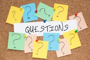 Picture of a pin board with post it notes and the word questions written out.