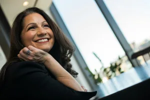 Leader looking out window with smile on face; reflecting on leadership and trends