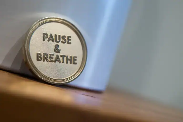 Close-up of a gold coin engraved with the words 'Pause & Breathe'—a visual reminder of Allison Shapira’s leadership mantra.