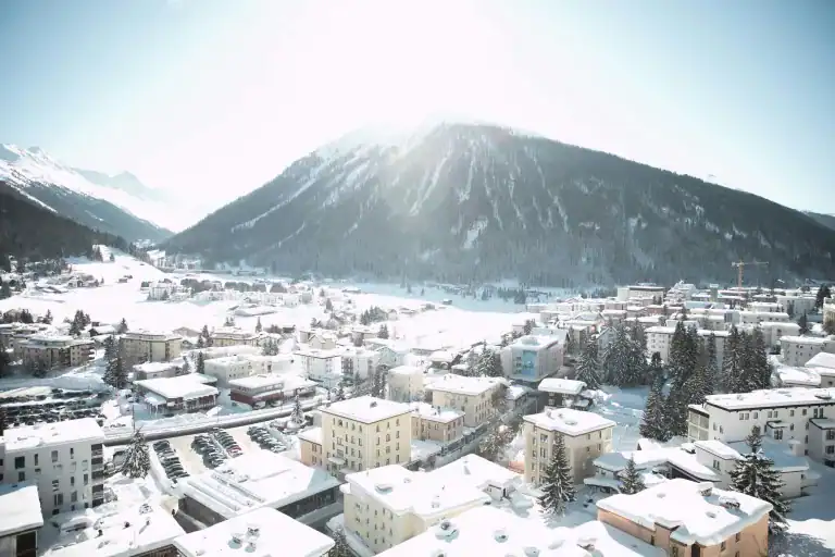 Bright winter sun over snow-covered rooftops and pine trees in Davos, Switzerland — Allison Shapira leadership blog post image about the decisions leaders can no longer avoid.