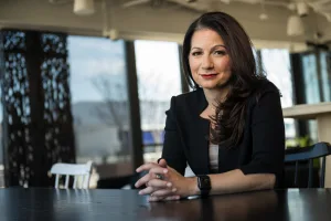 How to speak up in a meeting: Allison Shapira, leadership communication expert, seated at a conference table.